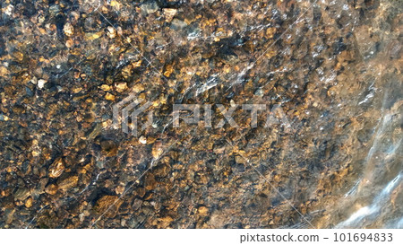 Top view on colorful pebbles covered by water. Close up view of smooth round pebble stones on the beach. Top view on colorful pebbles covered by water. Close up view of smooth round pebble stones on the beach. 101694833