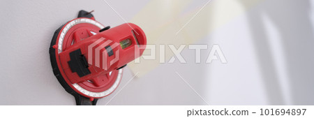 Red construction laser level fixed on white wall 101694897