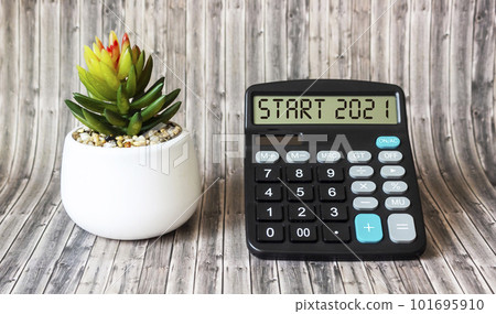 On the calculator, the text START 2021, next to a cactus flower on a wooden table. Planning 101695910
