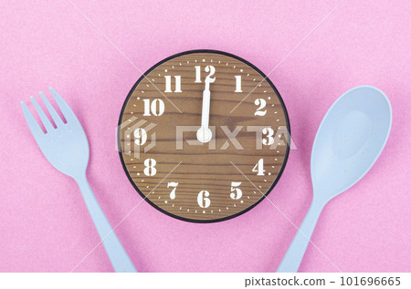 The Wooden clock with cutlery on pink color background. Concept of intermittent fasting, lunchtime, diet and weight loss 101696665