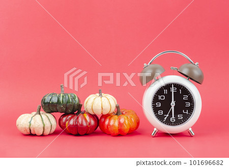 The Vintage alarm clock with autumn pumpkins on red background. 101696682
