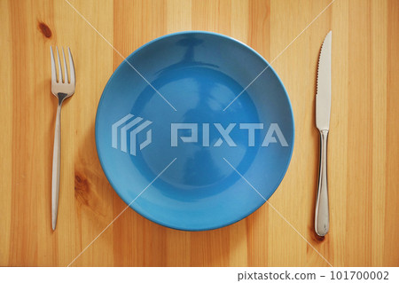 Empty and clean blue plate with fork and knife on a wooden table Empty and clean blue plate with fork and knife on a wooden table 101700002