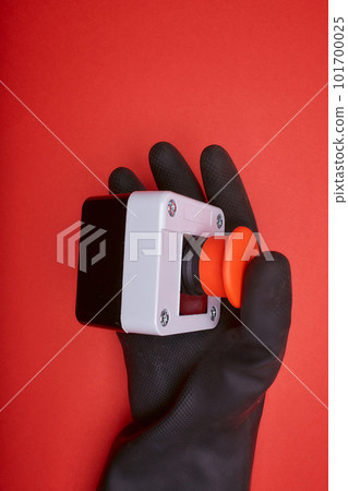 The hand in black resin glove, which pushes the emergency button at the red background at the side view 101700025