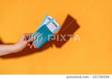 Tickets in passport in hand against yellow background under yellow light Tickets in passport in hand against yellow background under yellow light 101700398