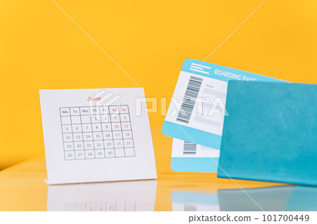 Air tickets in the passport next to the June calendar against yellow background Air tickets in the passport next to the June calendar against yellow background 101700449
