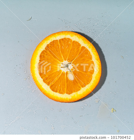 Sliced round piece of orange with pit on gray background Sliced round piece of orange with pit on gray background 101700452