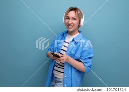 european adorable blond woman in shirt listening to music in wireless headphones on blue background european adorable blond woman in shirt listening to music in wireless headphones on blue background 101701814
