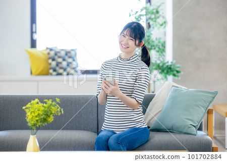 Young woman looking at her smartphone in the living room Young woman looking at her smartphone in the living room 101702884