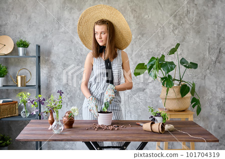 Portrait of Woman gardener transplanting plants. Concept of home garden. Flower and garden shop. A straw hat with a wide brim. Portrait of Woman gardener transplanting plants. Concept of home garden. Flower and garden shop. A straw hat with a wide brim. 101704319