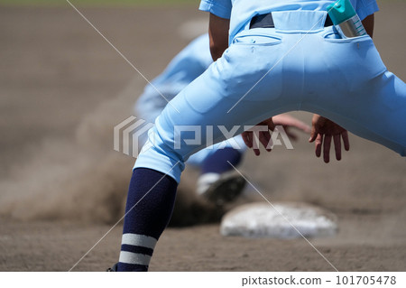 A runner aiming for the next base and a coach giving instructions to slide low during a baseball game A runner aiming for the next base and a coach giving instructions to slide low during a baseball game 101705478