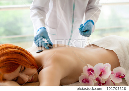 Young woman getting hot stone massage in spa salon. 101705828