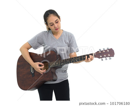 Asian woman in gray t-shirt and black pant playing acoustic guitar. Portrait on white background with studio light. Asian woman in gray t-shirt and black pant playing acoustic guitar. Portrait on white background with studio light. 101706180