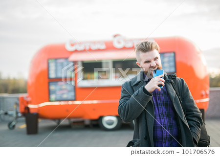Angry hungry man bites smartphone on background food truck - hunger and lack of money Angry hungry man bites smartphone on background food truck - hunger and lack of money 101706576