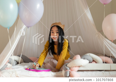 Happy girl with princess crown playing in her room. 101707808
