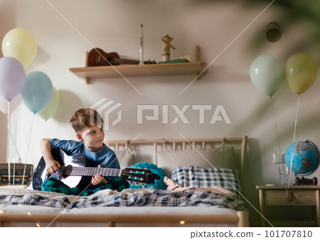 Happy boy playing on the guitar in his room. 101707810