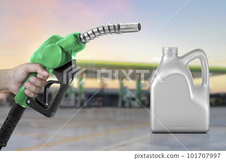 Engine oil nozzle against and bottle of engine oil. gas station blurred background. Energy fuel concept 101707997