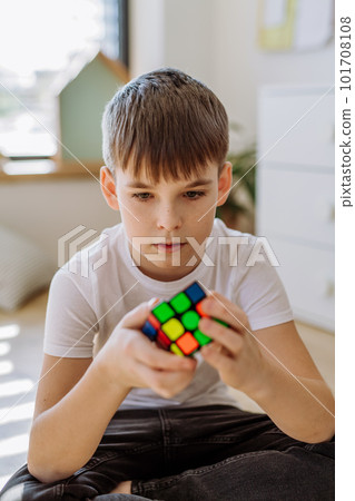Little boy playing with Rubiks cube in his room. Little boy playing with Rubiks cube in his room. 101708108