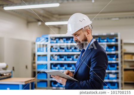 Manager in suit controlling goods in a warehouse. 101708155