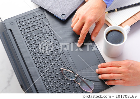 Image of both hands of a man working at a desk with a laptop Image of both hands of a man working at a desk with a laptop 101708169