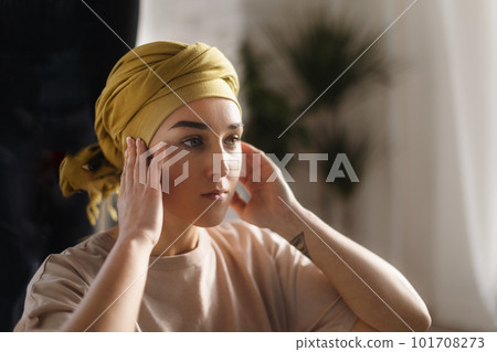 Portrait of young woman with cancer at home. 101708273