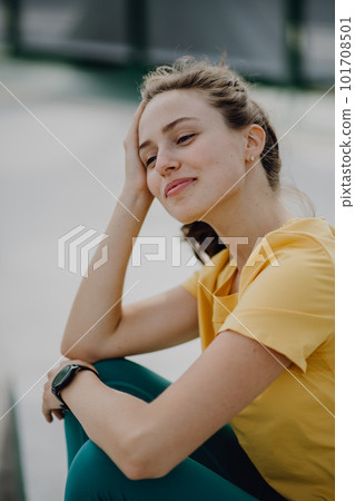 Portrait of young sportive woman resting outdoor in city. 101708501