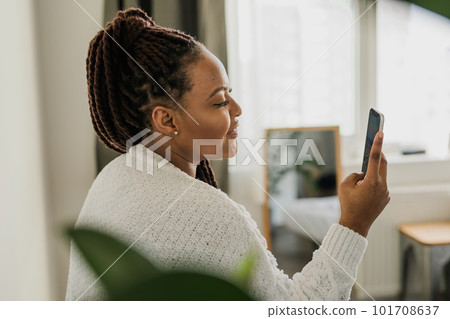 Portrait of African American female student dressed casually holding mobile phone and typing messages and communicating with friends via social networks using high-Internet connection. Portrait of African American female student dressed casually holding mobile phone and typing messages and communicating with friends via social networks using high-Internet connection. 101708637