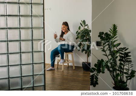 African american woman making video call in living room - social networks and connection 101708638