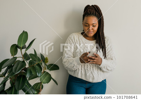 Portrait of African American female student dressed casually holding mobile phone and typing messages and communicating with friends via social networks using high-Internet connection. Portrait of African American female student dressed casually holding mobile phone and typing messages and communicating with friends via social networks using high-Internet connection. 101708641
