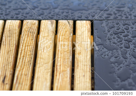 Wooden natural planks, polished boards, garden park bench with transparent big clear rain water drops on blue gray wet background. Empty place for recreation in bad weather. Wooden natural planks, polished boards, garden park bench with transparent big clear rain water drops on blue gray wet background. Empty place for recreation in bad weather. 101709193