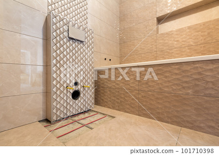 Unfinished reconstruction of bathroom or toilet with light beige geometric ceramic tiles installed on walls, place for lavatory and bath. Unfinished reconstruction of bathroom or toilet with light beige geometric ceramic tiles installed on walls, place for lavatory and bath. 101710398