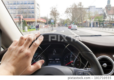 Steerind wheel with driver hand on it in modern car interior with view of street Steerind wheel with driver hand on it in modern car interior with view of street 101710555