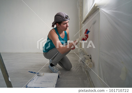 Woman paints the wall with a roller 101710722