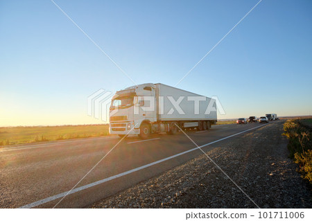 Semi-truck with cargo trailer driving on highway hauling goods in evening. Delivery transportation and logistics concept 101711006