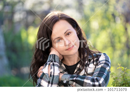 Portrait of thoughtful pretty young woman relaxing outdoors on warm spring sunny day. 101711070
