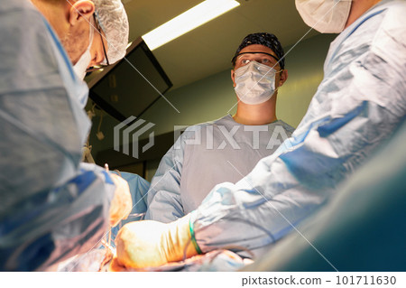 Surgeon face in operating room, stressful operation, surgeon performs operation in modern operating room with activity life support devices and light lamps, life saving, inoperable sarcoma. Surgeon face in operating room, stressful operation, surgeon performs operation in modern operating room with activity life support devices and light lamps, life saving, inoperable sarcoma. 101711630