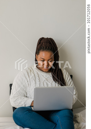 African american young woman using laptop on bed - technologies and communication and social network concept African american young woman using laptop on bed - technologies and communication and social network concept 101712056
