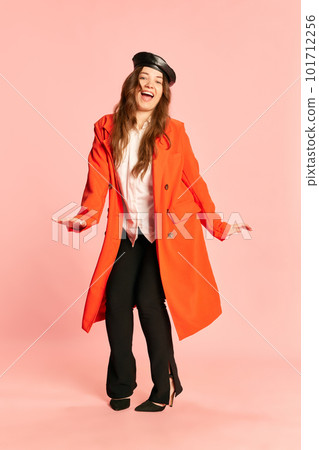 Portrait of beautiful woman wearing stylish clothes with beret, heels and red coat smiling over pink studio background. Jump for happiness Portrait of beautiful woman wearing stylish clothes with beret, heels and red coat smiling over pink studio background. Jump for happiness 101712256