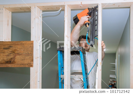 Using an air hammer builder nails wooden beams to frameworks of housing for construction house Using an air hammer builder nails wooden beams to frameworks of housing for construction house 101712542