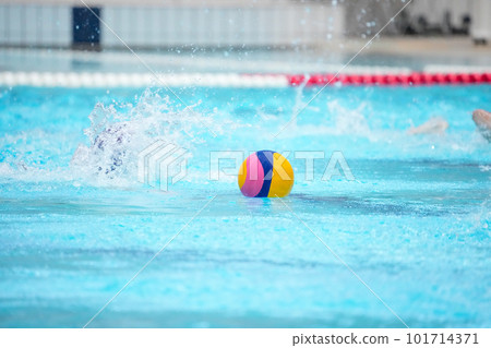 A player going to get the center ball floating in the center of the pool court immediately after the start of the water polo match A player going to get the center ball floating in the center of the pool court immediately after the start of the water polo match 101714371