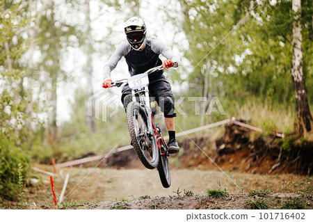 downhill mountain bike rider jump over springboard in forest trail race downhill mountain bike rider jump over springboard in forest trail race 101716402