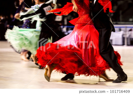 dance couple dancing waltz in competitive ballroom dancesport, woman is wearing red dress and black tail suit on man 101716409