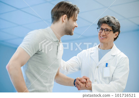 Male doctor holding his patients hand and supporting him 101716521