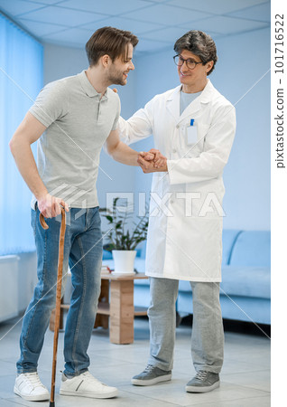 Nurse assisting a patient to walk with a stick Nurse assisting a patient to walk with a stick 101716522
