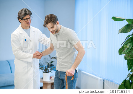 Nurse assisting a patient to walk with a stick Nurse assisting a patient to walk with a stick 101716524