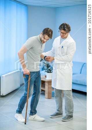 Nurse assisting a patient to walk with a stick Nurse assisting a patient to walk with a stick 101716525