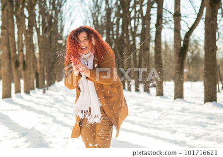 Fat caucasian woman playing snowballs in the park.  101716621