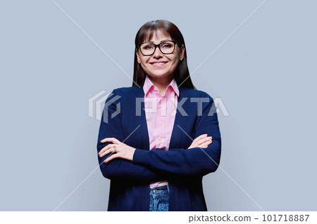 Positive middle aged woman posing over grey studio background 101718887