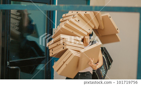 Fastfood meal courier dropping pizza boxes pile outside building, clumsy takeaway worker stumbling and running scared. Bad delivery service, pizzeria employee with falling packages. Handheld shot. 101719756