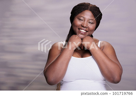 Smiling african american body positive woman holding hands under chin portrait. Curvy beautiful lady feeling happy, showing optimistic lifestyle and expressing positive emotions Smiling african american body positive woman holding hands under chin portrait. Curvy beautiful lady feeling happy, showing optimistic lifestyle and expressing positive emotions 101719766