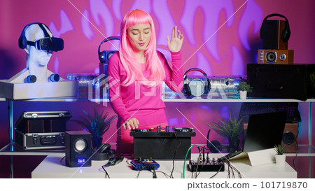 Artist with pink hair dancing and having fun in nightclub, mixing eletronic sound with techno using professional mixer. Dj performer playing remix using audio equipment, performing at musical event 101719870